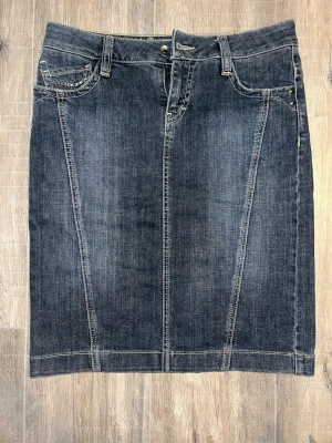 Jeanskjol från Esprit Denim 💙 -   Snygg mörk jeanskjol med dekorativa nitar och fina sömdetaljer. Sprund baktill med dragkedja. Stretchig och sitter väldigt snyggt på.  •Märke: Esprit Denim •Storlek: 36(S) •Färg: Mörkblå denim •Skick: Mycket bra •Detaljer: Nitar, fickor bak & fram, dragkedja bak  Perfekt Y2K vibe – snygg med boots, ballerinas eller sneakers ✨