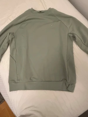 Ljusgrönt set från Nike dri fit - Snyggt ljusgrönt set från Nike med sweatshirt och matchande byxor. Tröjan har rund hals och diskret Nike-logga på bröstet, byxorna har dragsko i midjan och fickor. Båda delarna är i mjukt material, perfekt för en avslappnad look.