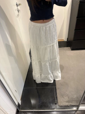Vit långkjol från SHEIN - Säljer en vit långkjol från SHEIN i storlek XS. Kjolen har resår i midjan och flera volanglager som ger en flowy och bohemisk vibe