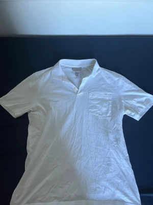 Vit slim fit skjorta från H&M - Klassisk vit skjorta från H&M i slim fit-modell. Skjortan har korta ärmar, bröstficka och knappar vid halsen. Tillverkad i mjuk bomull som känns skön mot huden. Perfekt till jeans eller shorts för en clean look.