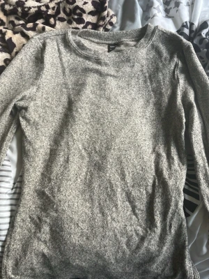 Grå basic tröja från SHEIN - En enkel och mjuk grå tröja från SHEIN i storlek S. Tröjan har rund halsringning och långa ärmar, perfekt för lager på lager eller som basplagg. Materialet är tunt och stretchigt för en bekväm passform.