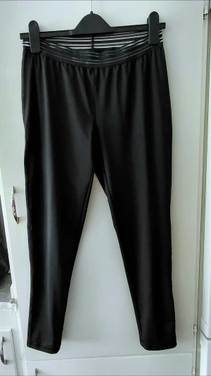 Crivit träningsbyxor, M - Svarta leggings med en snygg transparent randig detalj i midjan. Tight passform och stretchigt material som sitter skönt. Perfekta till en oversized hoodie eller crop top. Storlek M. Knappt använda.  