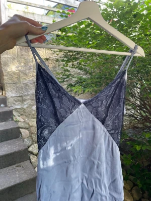 Ljusblå klänning från NA-KD - Säljer en ljusblått klänning från NA-KD med tunna axelband och v-ringning. Överdelen är dekorerad med svart spets som ger en elegant look. Materialet känns mjukt och svalt, perfekt för sommar
