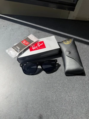  Ray-Ban Wayfarer solglasögon - Klassiska svarta Ray-Ban Wayfarer solglasögon med mörka glas. Kommer med originalfodral, putsduk och box. Perfekta för dig som vill ha en tidlös och stilren accessoar till sommaren. 