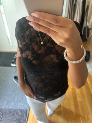 Svart spetsblus med blommönster - Säljer en svart, transparent spetsblus med blommigt mönster. 