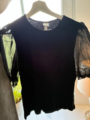 Svart topp med puffärmar från H&M - Säljer en svart topp från H&M med transparenta puffärmar, använt nån enstaka gång. Säljer pga lite för stor för mig. 