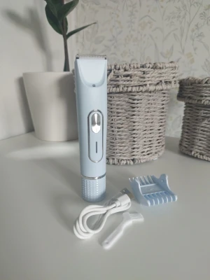 Ljusblå elektrisk hårtrimmer - Elektrisk hårtrimmer i ljusblå plast med silverfärgade detaljer. Ergonomisk och avlång form, med tillhörande kam, USB-laddningskabel och rengöringsborste. Perfekt för styling och trimning av hår. Modern design och enkel att använda. Endast upplockad och blivit liggandes. Ska inte användas i vatten. Köpt på CDON.