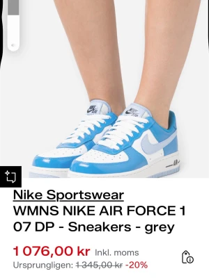Nike Air Force 1 blå/vit sneakers - Nike Air Force 1 sneakers i blått och vitt med klassisk låg siluett. Skon har vit sula, blått läder på ovandelen och vit mesh på tån samt ljusblå swoosh. Ikonisk Air-dämpning och perforerade detaljer för extra komfort och stil.