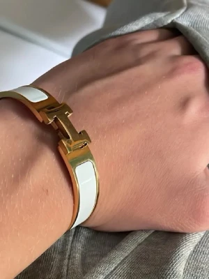 H armband - Säljer ett snyggt armband i vit och guld, perfekt för dig som gillar en stilren och modern look