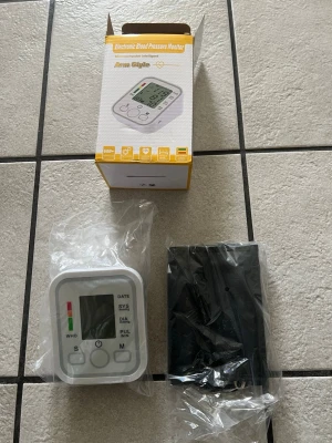 Elektronisk blodtrycksmätare  - Elektronisk blodtrycksmätare från Arm Style med digital display och tydliga knappar. Vit och grå design, levereras med manschett och förvaringspåse. Perfekt för att enkelt mäta blodtryck hemma. Material i plast och textil.