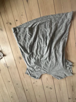 Grå t-shirt med glitterstjärnor - Säljer en grå t-shirt med korta ärmar och coola glitterdetaljer i form av stjärnor och blixt på framsidan. T-shirten har en avslappnad passform och är gjord i mjukt bomullsmaterial, perfekt för dig som gillar en enkel men ändå unik stil.