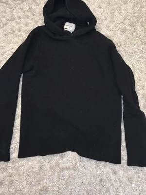 Merinoull hoodie - En stilren svart hoodie från VailentStudios med klassisk huva och långa ärmar. Tillverkad i mjukt material som känns skönt mot huden 100% merinoull. Perfekt för dig som gillar minimalistisk och clean stil. Passar till det mesta och är enkel att matcha. Finns ett mycket litet hål i nacken men mycket enkelt att fixa👍