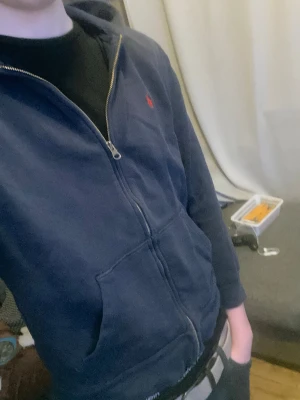 Mörkblå hoodie från Polo Ralph Lauren - Säljer en mörkblå hoodie med dragkedja från Polo Ralph Lauren. Har luva, två fickor och den röda Ralph Lauren loggan.