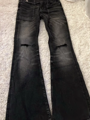 Svarta bootcut jeans  - Säljer ett par svarta bootcut jeans från gina young med hål vid knäna och  fickor fram. Jeansen har en tvättad look och dubbla knappar i midjan. Använt ungefär 2 gånger 