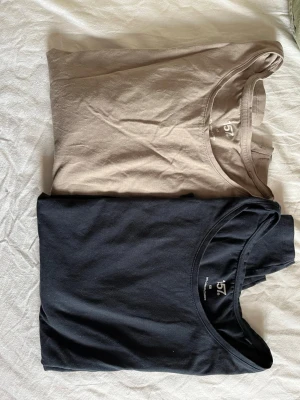 Två basic lång ärande tröjor från 157, XS - Säljer två basic tröjor från 157 i storlek XS. Ena tröjan är marinblå och den andra är beige. Båda har rund halsringning och är tillverkade i mjuk bomull med lite elastan för extra stretch. Perfekta till alla outfits och superbekväma.