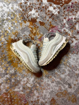 Nike Air Max 97 Ljusblåa sneakers - Säljer ett par Nike Air Max 97 sneakers i Ljusblått och vitt med ikoniska vågiga paneler och synlig Air-sula. Skorna har reflekterande detaljer, mesh och mocka i ovandelen samt klassisk Nike Swoosh på sidan. Perfekta för dig som gillar stilrena och sportiga sneakers.