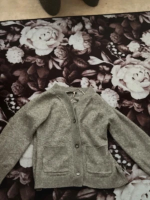 Grå stickad kofta med fickor - Mysig grå stickad kofta med knappar framtill och två stora fickor. Koftan har långa ärmar och ribbade muddar vid ärmslut och nederkant. Perfekt för lager på lager och enkel att matcha med olika outfits. Pris bilderna diskuteras  och mer info kom privat!!🥰