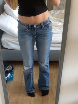 Blåa lågmidjade jeans med hål  - Hejj jag säljer de här blåa lågmidjade jeansen med röda sömmar, hål på knäna och detaljer på fickorna. Dessa jeansen är så snygga men jag säljer de pågrund av att jag börjar få för mycket jeans och behöver rensa garderoben. De är i storlek 164 vilket motsvarar ungefär S. De här passar om du har xs, S eller storlek 164. Jag är 165 cm lång💕💕 De har använts några gånger men har inga defekter. Jeansen säljs inte längre på ginatricots sida💕