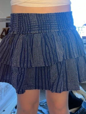 Blå volangkjol med vitt mönster - Kort blå volang-kjol med vita prickiga ränder och bred smock i midjan. Helt oanvänd med prislapp kvar❤️