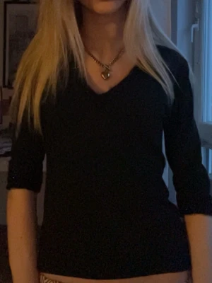 Svart topp med glitter på kragen och ärmarna🖤 - Snygg svart topp med v-ringning och glittrig kant runt kragen och ärmarna som är trekvarts från hennes