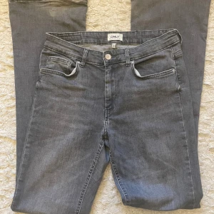 Grå jeans från ONLY, storlek L/34 - Snygga grå flare jeans från ONLY med klassisk femficksdesign. Jeansen har normal passform och är tillverkade i mjukt denimtyg. De är välanvända, man kan se det på slutet av jeansen. Men annars är jeansen i bra skick. Säljer dem för att de är för stora.