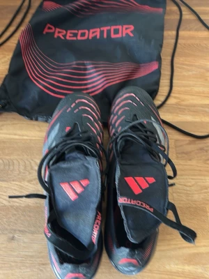 Adidas Predator fotbollsskor svart/röd - Säljer ett par Adidas Predator stealth victory med ag dobbar storlek 44.  Medföljer en svart och röd Predator-påse. Använda runt en månad. Köpte de för 2999kr. Pris kan självklart diskuteras, skriv om du har några frågor🙌🙌