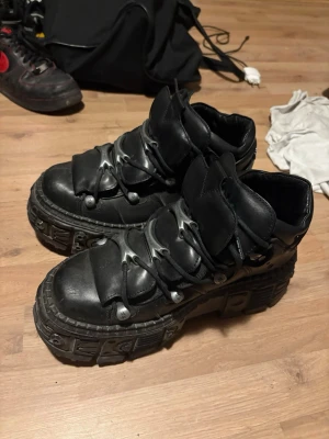 New Rocks stl 44 - Intressekoll.Säljer ett par svarta boots från New Rock med rejäl platåsula och metalliska detaljer över foten. Skorna har en chunky design och är tillverkade i läder med robust gummisula. Perfekta för dig som gillar alternativ stil och vill sticka ut.