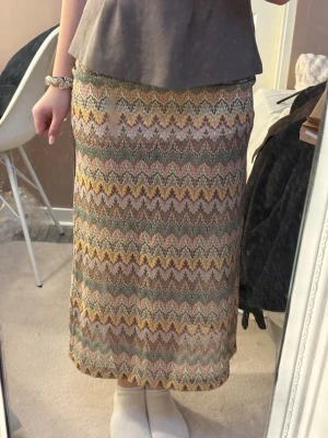 Missoni liknande kjol - Säljer en långkjol med vågigt mönster i pastelliga toner av gult, grönt, rosa och beige. Kjolen har en rak passform och är tillverkad i ett mjukt, stretchigt material som känns bekvämt mot huden. Perfekt för dig som gillar färg och mönster!