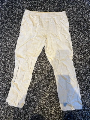 Beige linnebyxor med rak passform - Snygga beige linnebyxor med rak passform och klassisk look. Byxorna är tillverkade i ett lätt och luftigt linnetyg som passar perfekt för en avslappnad stil. Perfekta att matcha med en enkel t-shirt eller skjorta.