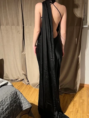 Exklusiv bal-/festklänning från Kaoā– NY med lapp & box - Säljer en helt ny, oanvänd klänning från Kaoā – perfekt till bal, gala eller annan fest. Klänningen är fortfarande med lapp kvar och kommer i originalbox. Modell: Hellång, figurnära med elegant släp Detaljer: Halterneck med drapering framtill och öppen rygg med vackert fall baktill Skick: Helt ny (endast provad) Nypris: 3550 kr. Säljes för: 3000 kr storlek: s jag är 178.  En otroligt elegant och stilren klänning som verkligen gör intryck – perfekt om du vill sticka ut på balen eller festen. 