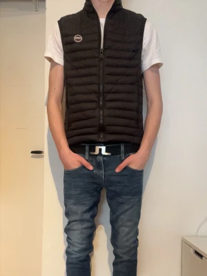 Svart dunväst från Colmar - Snygg svart dunväst från Colmar med quiltad design och dragkedja framtill. Västen har en hög krage och ett stilrent Colmar-märke på bröstet. Perfekt att slänga över en hoodie eller t-shirt för en cool look. Modellen är 185cm men västen sitter lite liten på honom! Priset är inte hugget i sten!🔥🤞💸