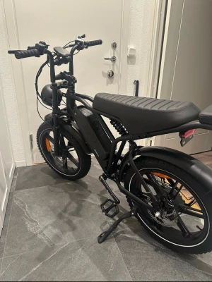 Svart elcykel Rode - Säljer en svart elcykel från Rode med breda däck, lång sadel och robust ram. Cykeln har skivbromsar, batteri monterat på ramen och stora fram- och baklampor. Perfekt för dig som vill ha en cool och kraftfull elcykel.