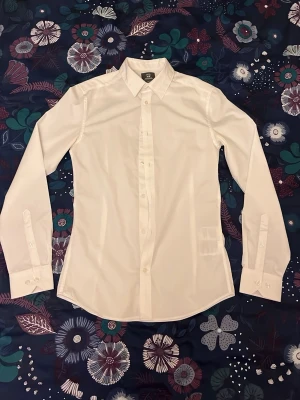 Skjorta H&M - Klassisk vit button-down skjorta från H&M i slim fit. XS. Passar det mesta men särskilt för finare stunder, hör av vid fundering !