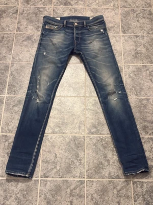 Diesel jeans - Snygga blå diesel jeans med slitningar och ljusa partier framtill. Jeansen har klassisk femficksdesign. Perfekta för en trendig och avslappnad stil.
