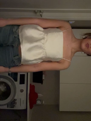 Champagnefärgad satinlinnetopp festtopp Från Gina tricot!  - Snygg champagnefärgad linnetopp i satin med tunna axelband och rak halsringning. Toppen har en lätt volang nedtill och är perfekt att styla med jeans eller kjol för en trendig look. Perfekt för sommaren och sitter väldigt bra!!