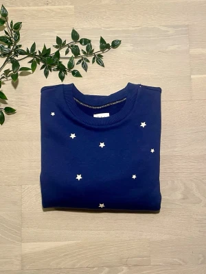 Blå sweatshirt stjärnmönster | Saint Tropez | XS/34 | Ny  - Säljer denna söta och mysiga sweatshirt från Saint Tropez med ett stjärnmönster över hela plagget i den vackra färgen “Midnight Sail Stars” — mörkblå med vita stjärnor. En liten gulddetalj längs halsringningen ger den ett extra fint touch. Originallappar kvar, helt oanvänd. Märke: Saint Tropez Modell: ZagnaSZ Sweat Pullover Färg: Midnight Sail Stars (mörkblå/stjärnmönster) Storlek: XS Skick: Helt ny med lappar kvar Ordinarie pris: 499 SEK Axelbredd: 45 cm Längd: 58 cm Frakt tillkommer.