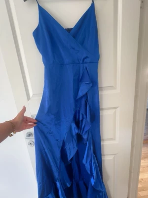 Blå supersnygg satin balklänning - Snygg blå balklänning med slits och volanger. I nyskick!! Pris kan diskuteras.