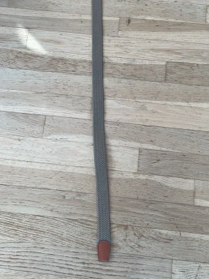 Beige flätat bälte från Jack & Jones - Säljer ett snyggt beige flätat bälte från Jack & Jones med detaljer i brunt skinn och silverfärgat spänne. Perfekt för att ge din outfit en stilren touch. Bältet är flexibelt och har en klassisk design som passar till många olika looks.