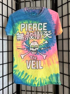 💀 PIERCE THE VEIL Tie-Dye Tour Tee 💀 - Emocore / Scene / Y2K Alt  Officiell Pierce The Veil merch från deras tie-dye turnéera. Rainbow batik med skull & crossbones + japansk text. Tryckt på Gildan Heavy Cotton (100% bomull).  Riktig 2010s alt-era vibe. Funkar perfekt till baggy jeans, cargos eller lager över longsleeve.  Storlek: S Mått: • Längd ca 56–57 cm • Bredd ca 50–52 cm  Skick: Bra vintage skick. Trycket är något blekt/krackelerat (ger mer autentisk tour-känsla, ej sprucket sönder). Inga hål.  Detta är inte ny reprint – äldre 