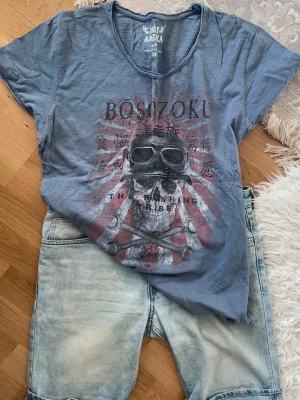 DAILY AMERICA blå t-shirt, storlek XXL - Cool blå t-shirt från Daily med BOSOZOKU-tryck och motiv av dödskalle med goggles och verktyg. T-shirten har rund halsringning och korta ärmar. Perfekt för dig som gillar streetstyle och unika prints.