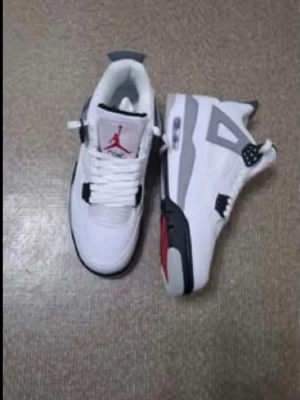 Air Jordan 4 White Cement sneakers - Säljer ett par Air Jordan 4 White Cement sneakers med vit ovandel i mesh och läder, grå och svarta detaljer samt röda inslag på tungan. Klassisk siluett med synlig Air-enhet i sulan och ikoniska plastdetaljer på sidorna. Perfekta för dig som gillar streetwear och retrostil.