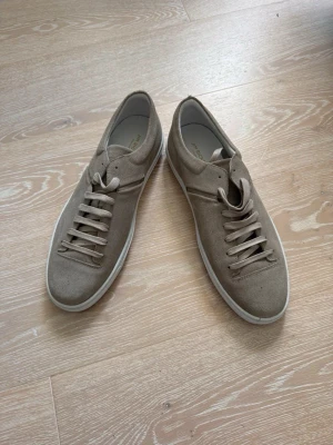 Grå mockasneakers från Jim Rickey - Nya - Snygga grå sneakers från Jim Rickey i mocka med vita gummisulor och klassisk låg profil. Skorna har ton-i-ton snörning och stilren design som passar till det mesta. Perfekta för dig som gillar minimalistisk och clean stil. Skorna är helt nya!