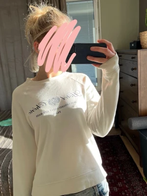 Vit sweatshirt med tryck - Säljer en vit sweatshirt med tryck på bröstet i grått och svart. Tröjan har rund halsringning och långa ärmar, samt en avslappnad passform. Perfekt inför våren. Jag säljer denhär skit snygga tröjan eftersom den ej kommer till användning men tycker dock att den är skut snygg, den är från märket Holly&White och köpt ifrån Lindex. Storleken är M men känns som S