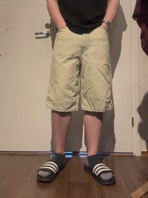 Beige baggy shorts i bomull - Säljer ett par beigea loose-fit shorts i bomull med klassisk femficksdesign. De har normal midja och går ner till knäna, perfekta för en avslappnad stil. Passar dig som gillar bekväma och rymliga shorts till sommaren.