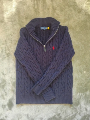 Polo Ralph Lauren - grovstickad - kabelstickad - tröja - Hej! Säljer en stilren oanvänd Ralph Lauren half zip up med kabelstickning, Tröjan är i färgen marinblå med en skön passform längst med hela kroppen. Tröjan säljs för ett billigt pris för endast 500kr då ja inte tyckte om hur jag såg ut i den👍🏼 Hör gärna av dig fövud minsta lilla fråga! 🫶🏼