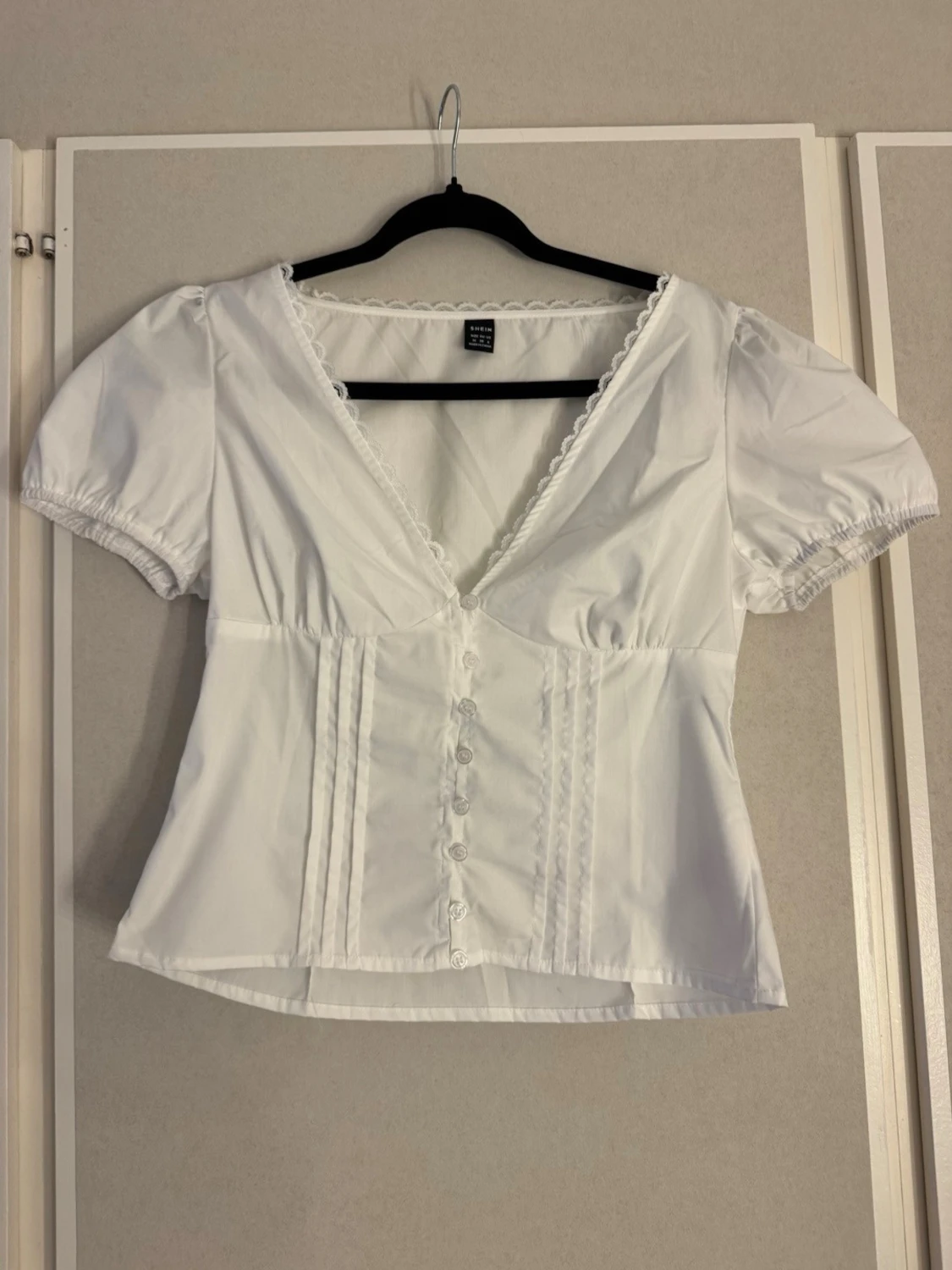 Vit topp med v-ringning och spetsdetaljer
