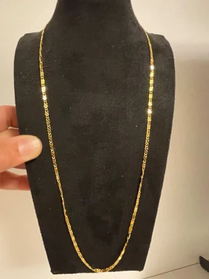 Guldpläterat Figarolänk halsband med guld 18k - Snyggt halsband med klassisk figarolänk i guldpläterad metall. Kedjan har en tunn och elegant design med blanka, platta länkar som reflekterar ljuset. Perfekt för dig som gillar stilrena accessoarer med lite extra bling. Stämpeln med 18k finns vid låset
