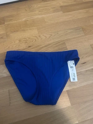 Blå ribbad bikiniunderdel H&M - Snygg blå bikiniunderdel från H&M med ribbad struktur. Klassisk modell med medelhög midja och mjukt stretchigt material som sitter skönt. Perfekt för strand eller poolhäng i sommar.