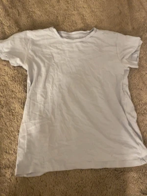 Vit basic t-shirt från 157 - En enkel blå t-shirt från 157 i storlek XS. T-shirten har klassisk rund halsringning och korta ärmar. Tillverkad i mjuk bomull som känns skön mot huden. Perfekt att matcha med jeans eller shorts för en clean look.