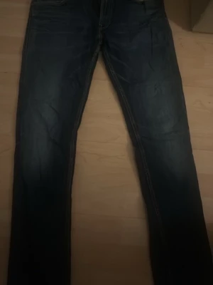 Mörkblå raka jeans replay - Säljer ett par mörkblå jeans med raka ben och klassisk femficksmodell. Jeansen har kontrastsömmar och lätt slitna detaljer framtill för en avslappnad look. Perfekta till vardagsstilen och passar till det mesta.